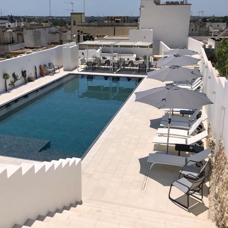 Infinity pool with sun deck, loungers and umbrellas at Zahra Superior Suite in Sannicola
